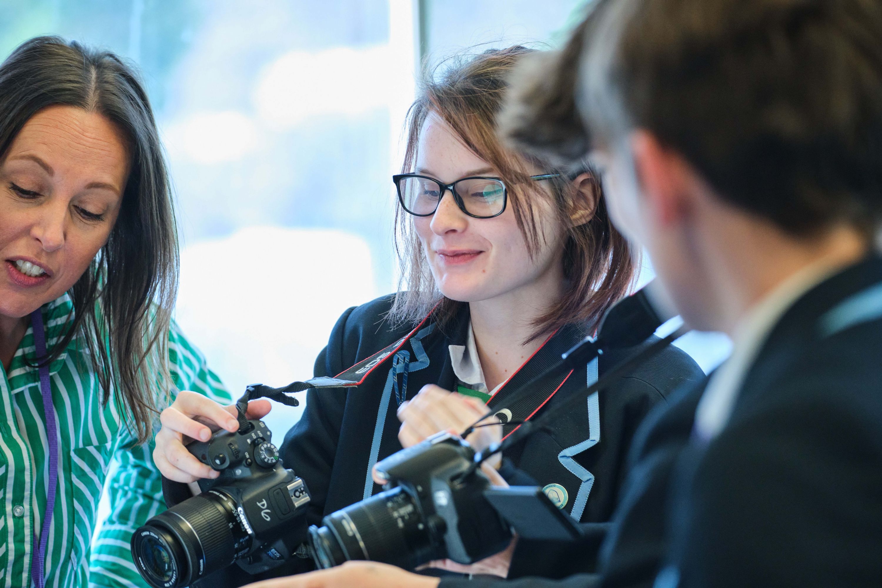 Female teacher and student holding cameras