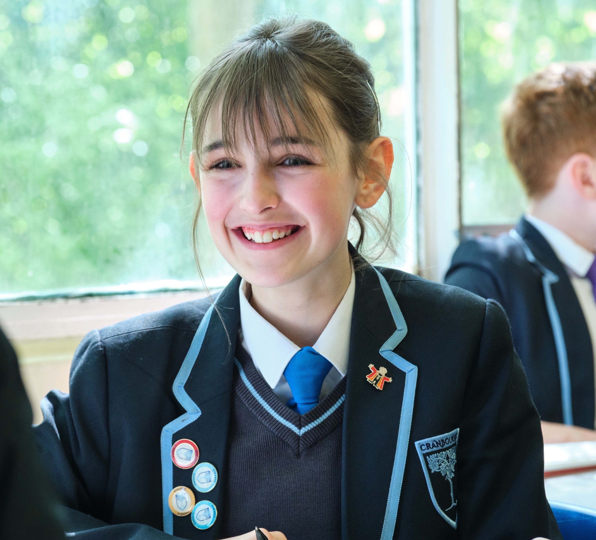 Female student with a blue tie smiling towards the camera