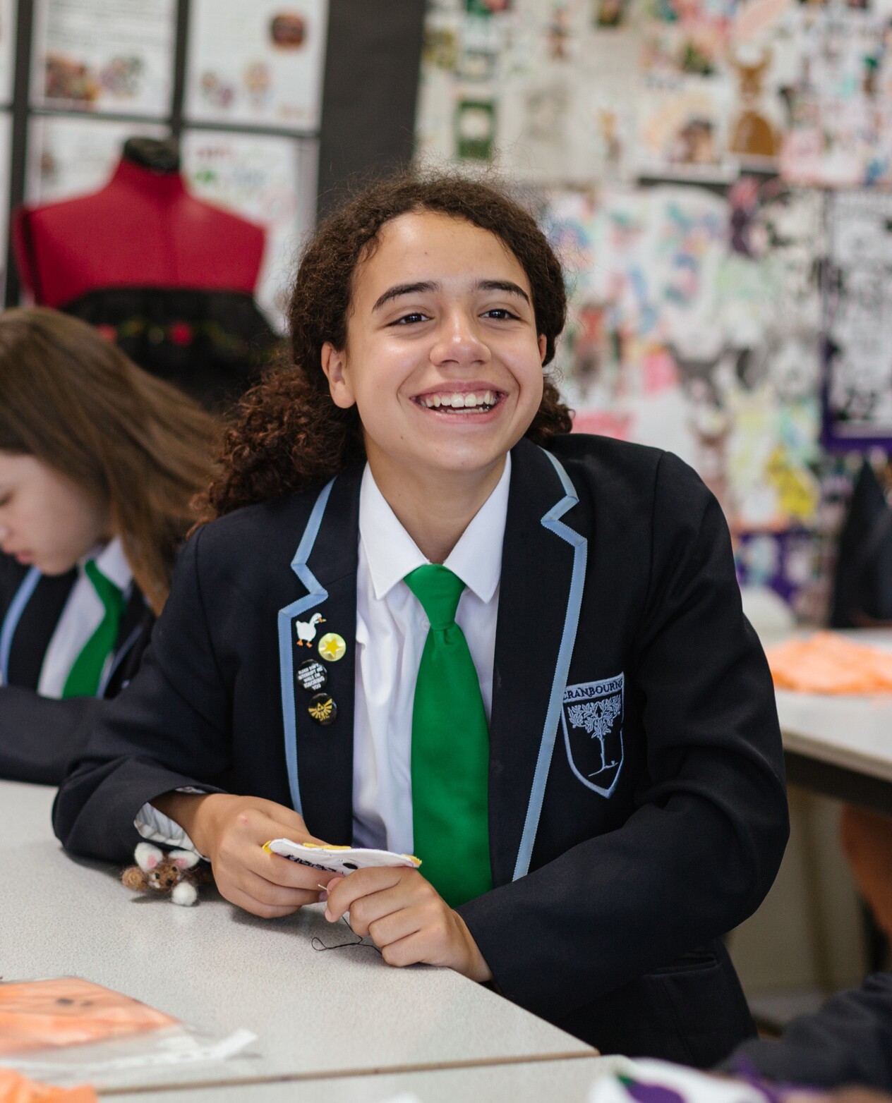 Female student with a green tie smiling towards the camera
